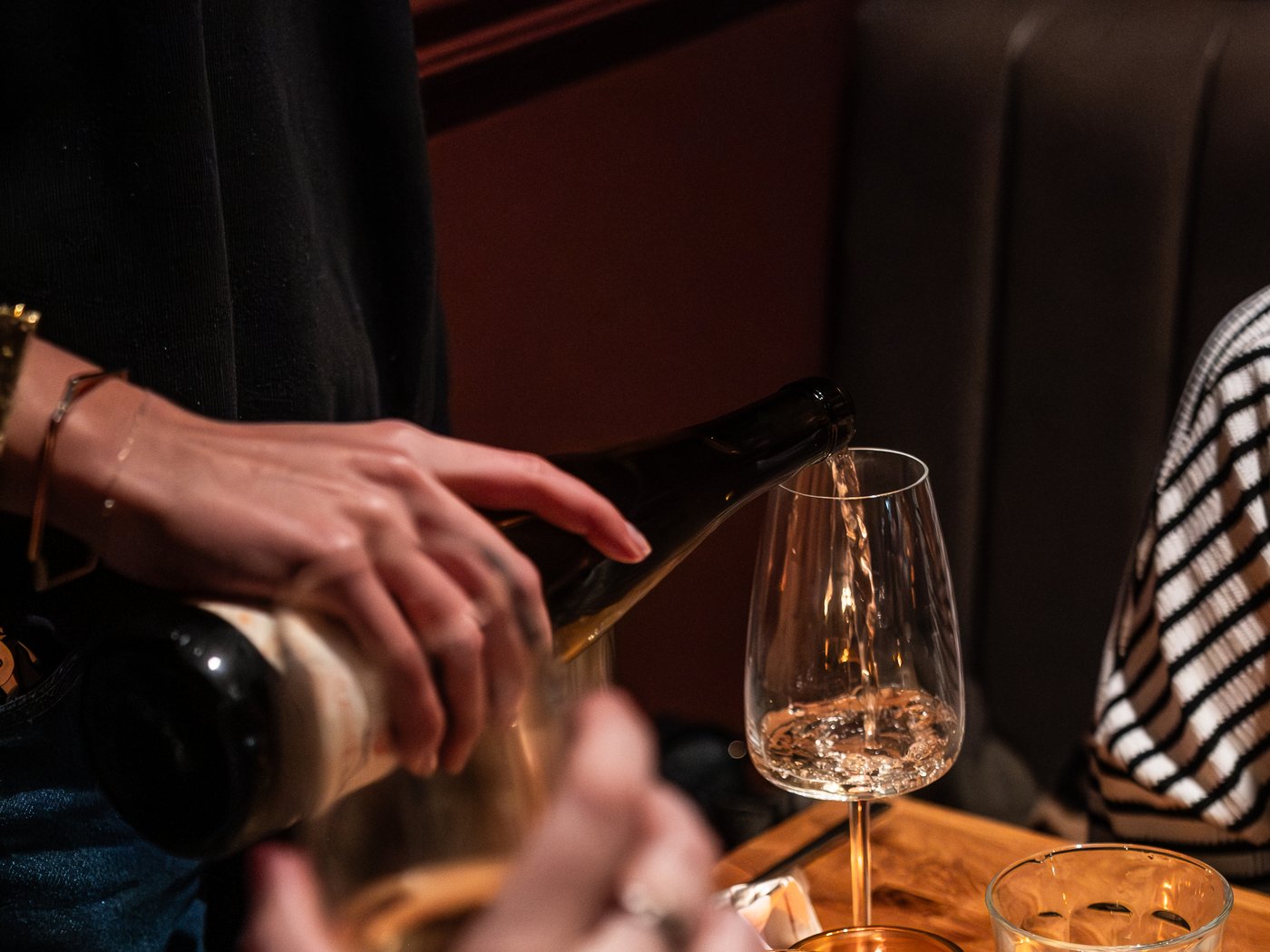 Wine being poured into a glass at a candlelit table